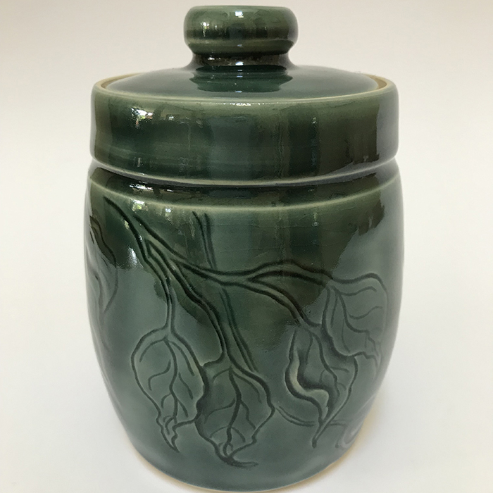 Item 473<br>White stoneware lidded pot with carved leaves. in a teal green celadon glaze<br>5.0 in tall by 3.25 in wide<br><b>$90</b>