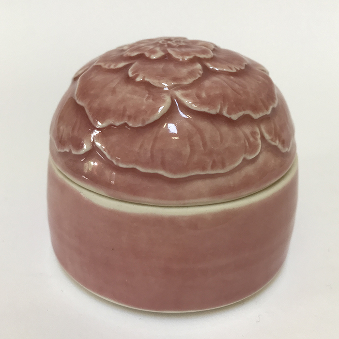 Item 54<br>Porcelain lidded pot with carved flower lid in a pink celadon glaze<br>2.25 in tall x 3.0 in wide<br><b>Sold</b>