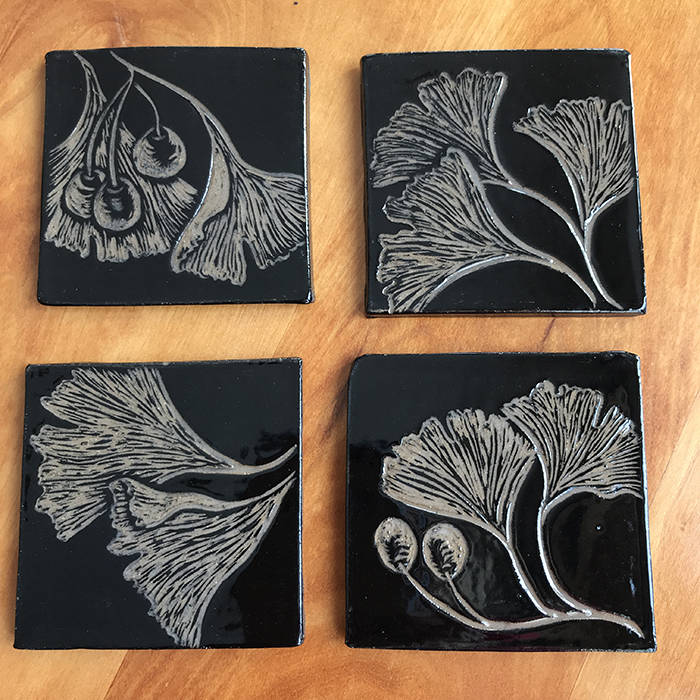 Item 408<br>Sgraffito coasters on brown clay with carved gingko leaves<br>3.25 in wide x 3.25 in tall